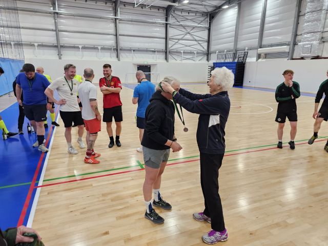 Losing finalist p;ayer receiving his medal from DameMary Peters